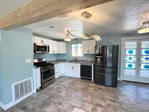 Kitchen with appliances with stainless steel finishes, white cabinets, a textured ceiling, dark wood-style floors, and hanging light fixtures