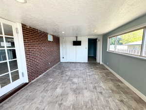 Interior space featuring brick wall, wood finished floors, and a textured ceiling