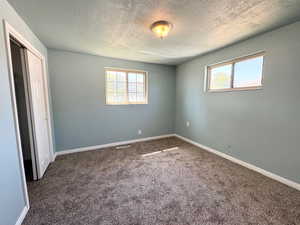 Unfurnished bedroom featuring dark carpet, a closet, and a textured ceiling