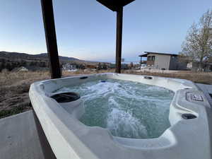 Pool at dusk with a hot tub and a mountain view