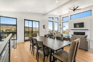 Dining space featuring a fireplace, light wood-type flooring, beamed ceiling, a ceiling fan, and recessed lighting