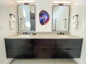Full bath with light tile patterned floors and double vanity