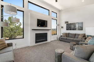 Carpeted living area featuring a fireplace and a high ceiling