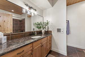 Bathroom featuring vanity, dark tile patterned flooring, wooden ceiling, and tiled shower