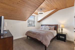 Bedroom featuring dark colored carpet, wood ceiling, and lofted ceiling