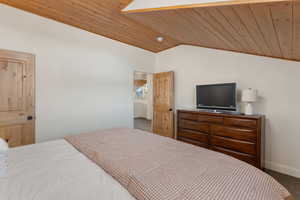 Bedroom featuring wooden ceiling, lofted ceiling, and carpet flooring