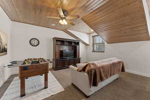 Carpeted living room with wood ceiling, lofted ceiling, and a ceiling fan
