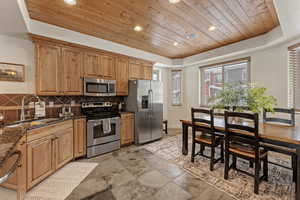 Kitchen with wooden ceiling, recessed lighting, appliances with stainless steel finishes, dark stone countertops, and backsplash