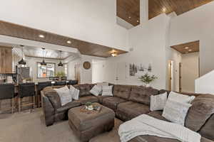 Carpeted living room featuring wood ceiling, a high ceiling, and recessed lighting