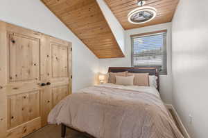Bedroom featuring lofted ceiling, wooden ceiling, and a closet