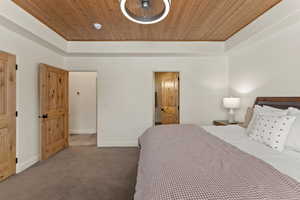 Bedroom featuring wood ceiling, carpet floors, and ensuite bath