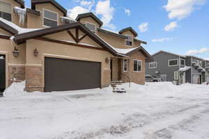 View of front of property featuring stone siding, stucco siding, a garage, and a residential view