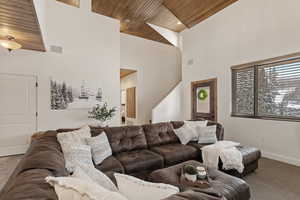 Carpeted living room featuring wood ceiling, recessed lighting, and a towering ceiling