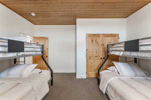 Bedroom with wooden ceiling and carpet flooring