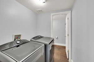 Washroom with a textured ceiling and washing machine and dryer