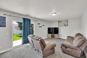Carpeted living area with a textured ceiling and baseboards