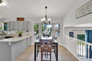 Dining room featuring healthy amount of natural light, a chandelier, vaulted ceiling, and light tile patterned floors