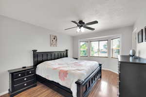 Bedroom with wood finished floors, a textured ceiling, and a ceiling fan