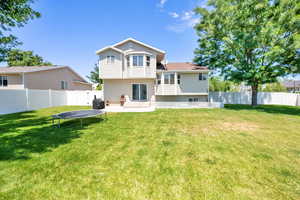 Back of property featuring a patio, a fenced backyard, and a trampoline