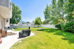 Fenced backyard featuring a patio area, a trampoline, and a mountain view