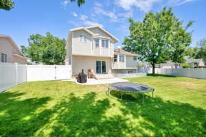 Back of property with a patio, a fenced backyard, a trampoline, and a gate