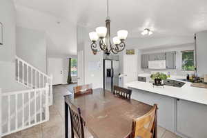 Dining space featuring stairs, lofted ceiling, a chandelier, and light tile patterned floors