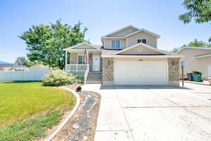 View of front of house with driveway, a garage, brick siding, and covered porch