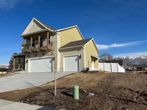 View of front of home featuring a balcony, concrete driveway, a shingled roof, a mountain view, and an attached garage