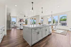 Kitchen featuring pendant lighting, a glass covered fireplace, a center island with sink, recessed lighting, and light stone countertops
