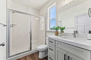Bathroom with a stall shower, vanity, and dark wood-style floors
