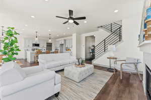 Living area featuring dark wood-style flooring, recessed lighting, stairs, a fireplace, and ceiling fan
