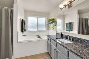 Full primary bathroom with separate bath and shower, vanity, light tile patterned floors, and granite counter