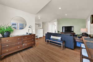 Living room featuring lofted ceiling, light wood flooring, and recessed lighting