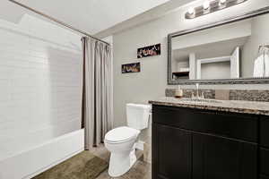 Bathroom with shower / bath combo, vanity, granite counter, and light tile patterned flooring