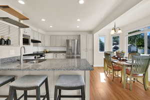 Kitchen with granite counters, recessed lighting, appliances with stainless steel finishes, light wood flooring, and hanging light fixtures