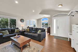 Living room with vaulted ceiling, light wood finished floors, and recessed lighting
