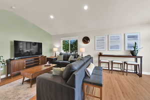 Living room with light wood floors, recessed lighting, and vaulted ceiling