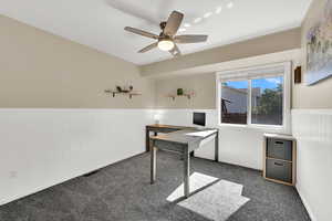 Home office or bedroom with wainscoting, carpet, and a ceiling fan