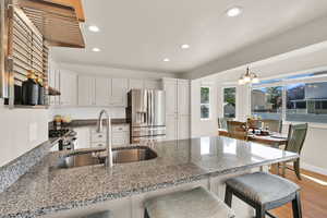 Kitchen featuring a kitchen breakfast bar, a peninsula, white cabinets, recessed lighting, and appliances with stainless steel finishes