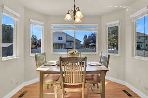 Dining area with light wood floors, plenty of natural light, and a chandelier