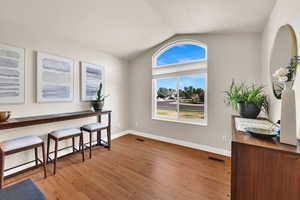 Formal living room space featuring lofted ceiling and light wood flooring