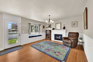 Formal dining or living area featuring a wainscoted wall, light wood floors, a gas fireplace, a chandelier, and a decorative wall