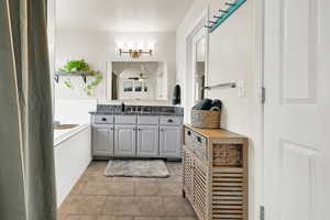 Full primary bathroom with vanity, separate bath and shower, light tile patterned flooring, and a ceiling fan