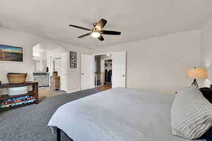 Primary bedroom featuring carpet, arched walkways, ceiling fan, and connected primary  bathroom