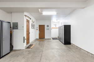 Hall with concrete flooring, electric panel, and a barn door