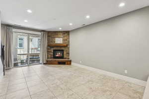 Unfurnished living room with recessed lighting, a stone fireplace, and light tile patterned floors
