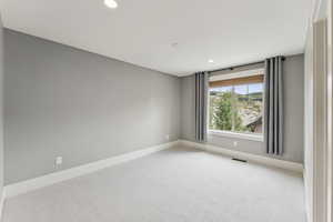 Carpeted spare room featuring baseboards and recessed lighting