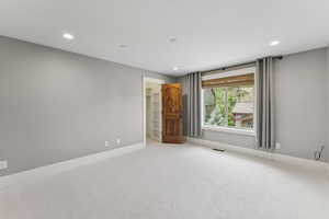 Carpeted spare room with baseboards and recessed lighting