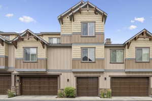 Craftsman house featuring board and batten siding, a garage, stone siding, and driveway