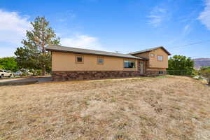 View of side of property featuring stucco siding, stone siding, and a shingled roof